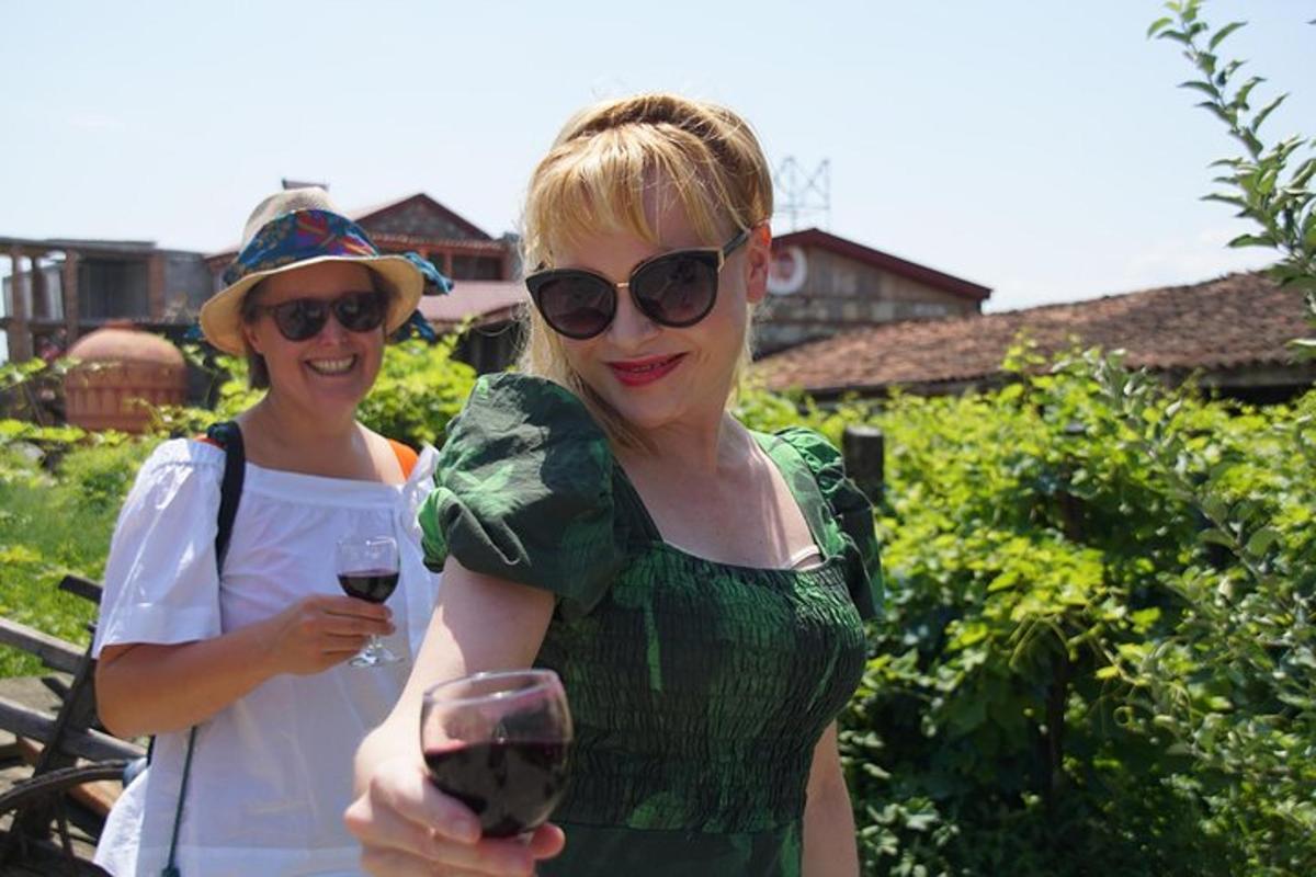 due donne in piedi in un vigneto con in mano un bicchiere di vino