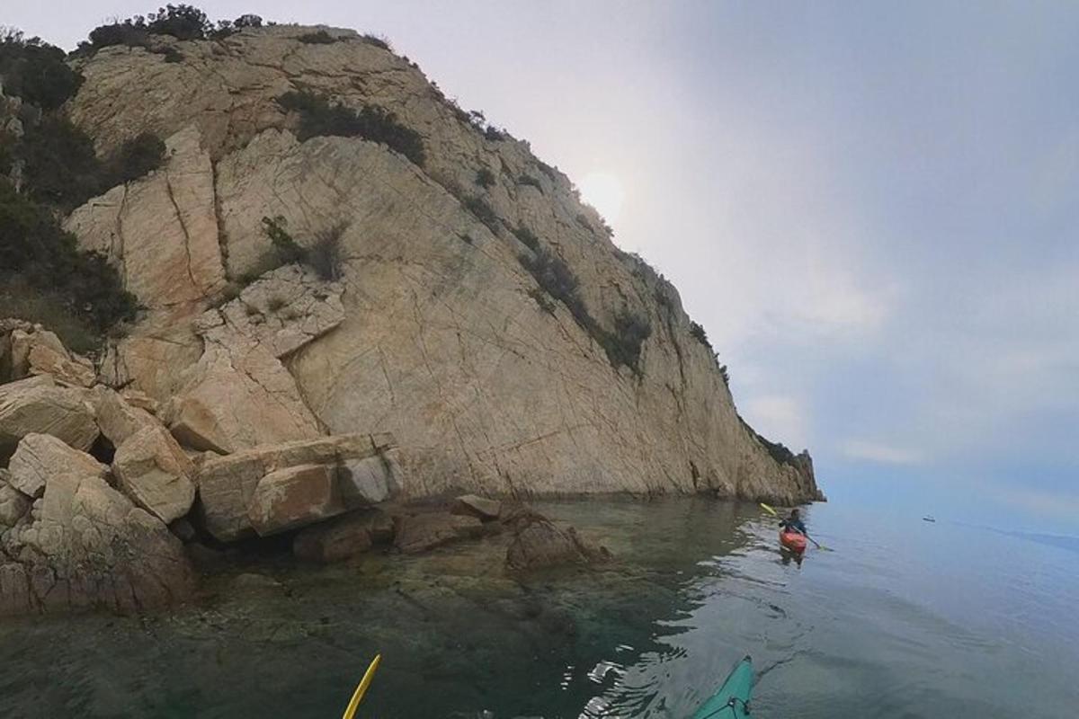 una persona che fa kayak in acqua vicino a una scogliera