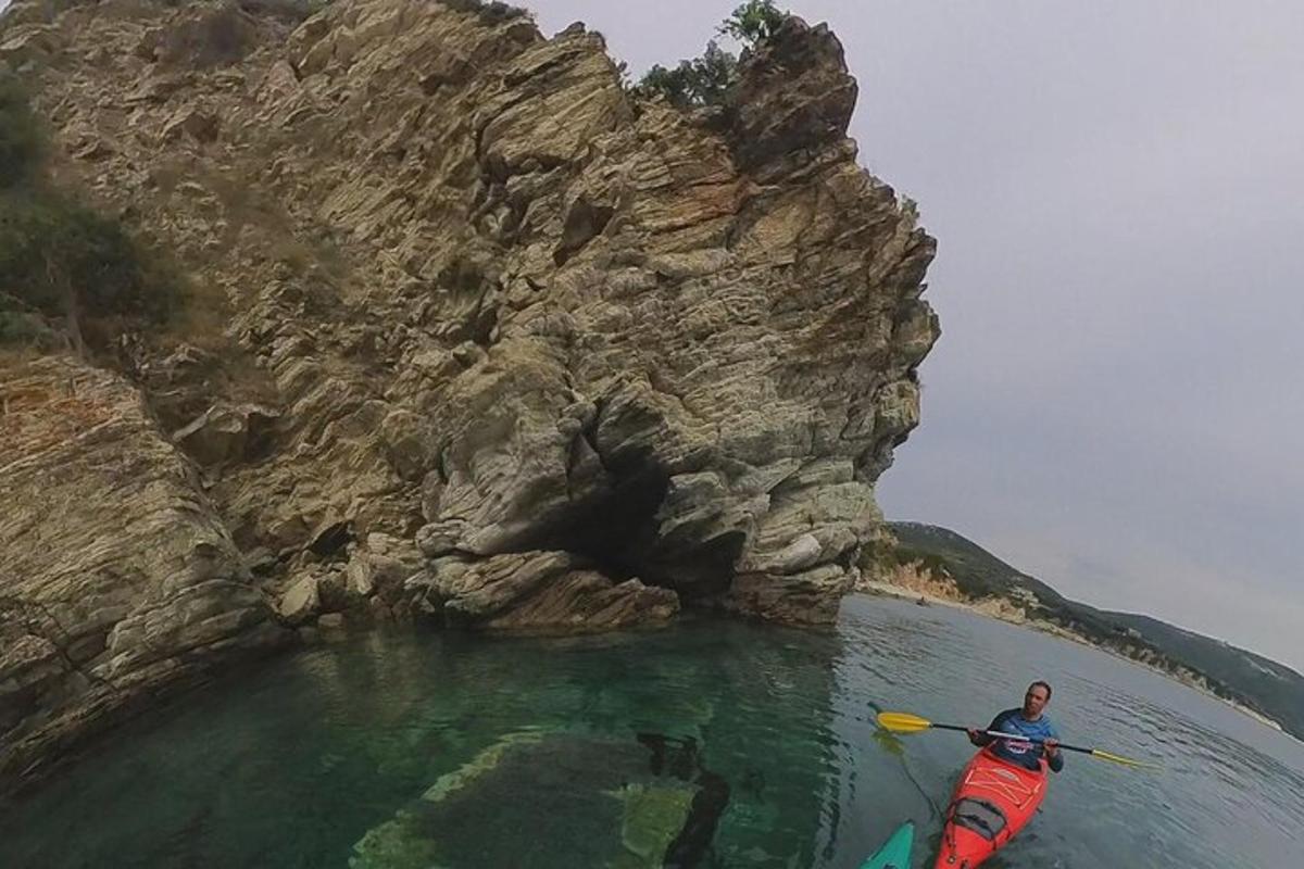 seorang pria di kayak di air di sebelah gunung