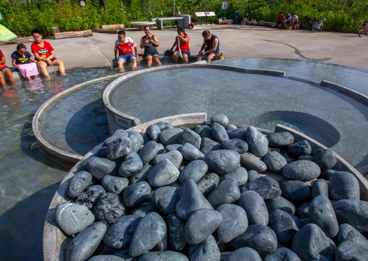 a group of children sitting in a pool of water with rocks