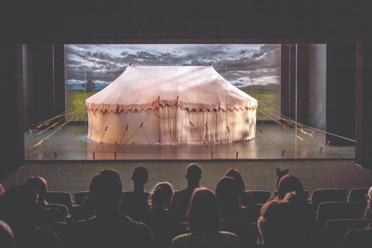 an audience watching a stage with a tent on it