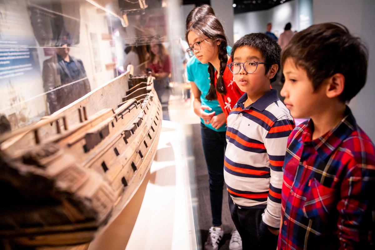 a woman and two children looking at a display in a museum