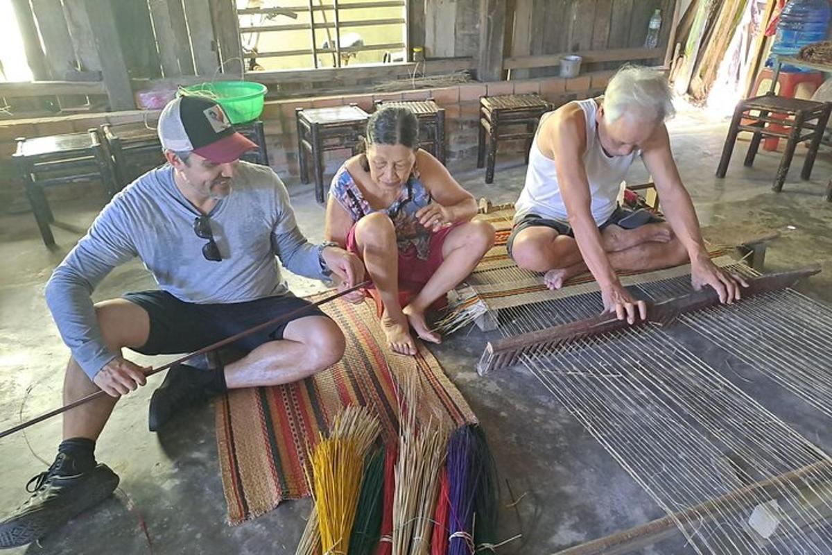 Un grupo de tres personas trabajando en una pieza de tejido.
