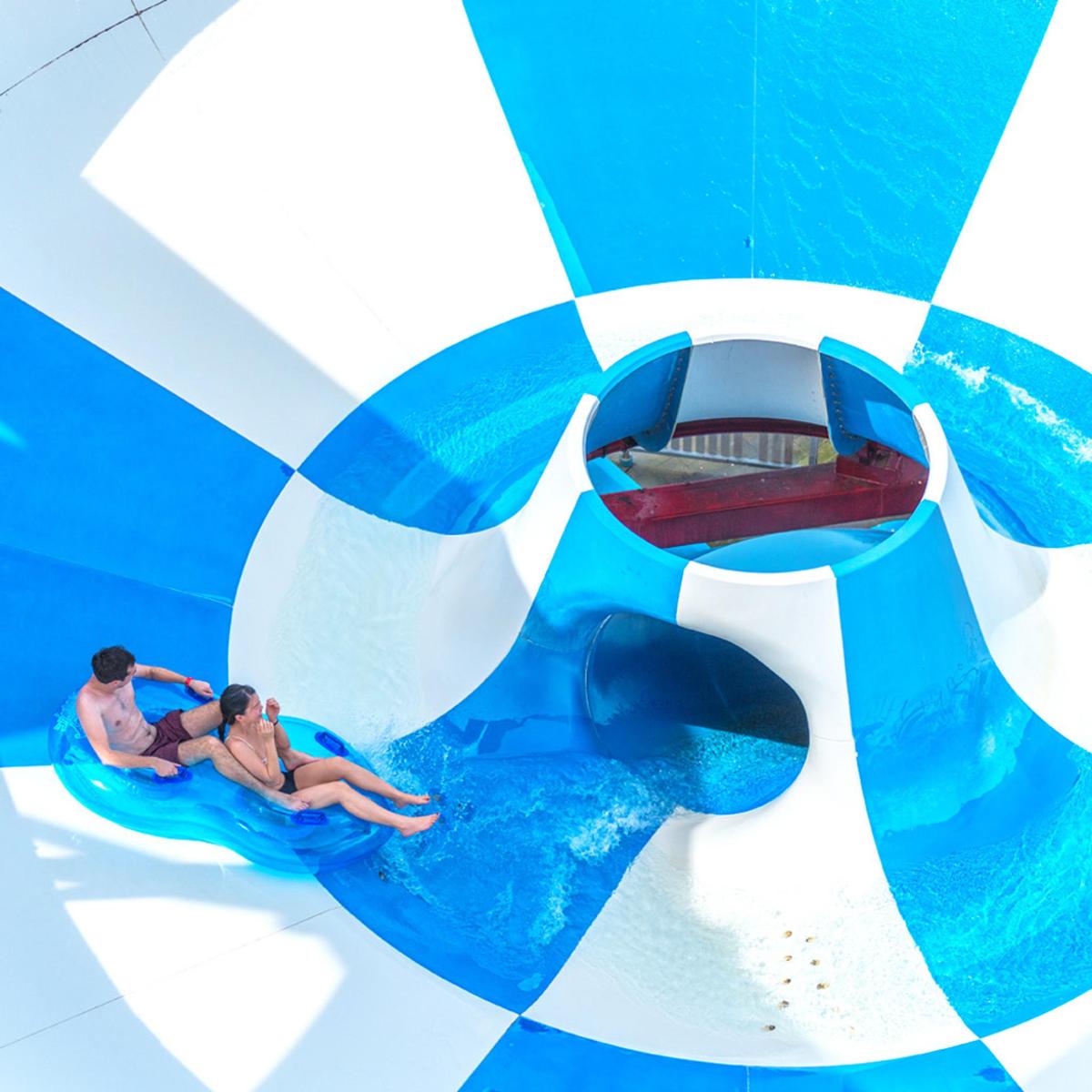 two people riding on a wave ride in a water park