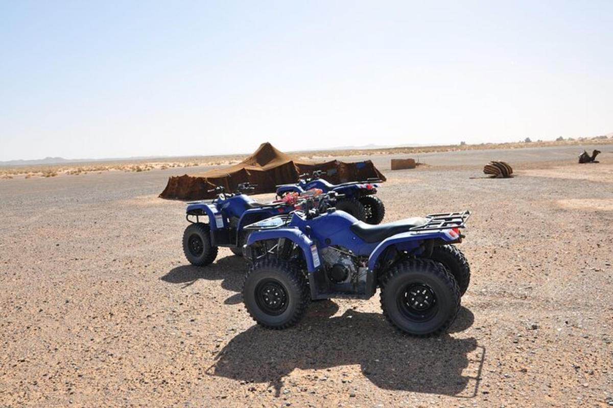 dua ATV diparkir di gurun dengan tenda