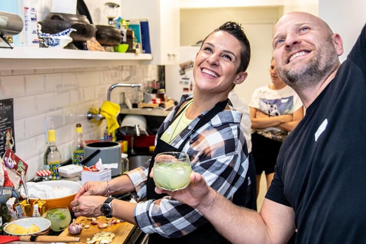 Un hombre y una mujer de pie en una cocina sosteniendo una bebida.