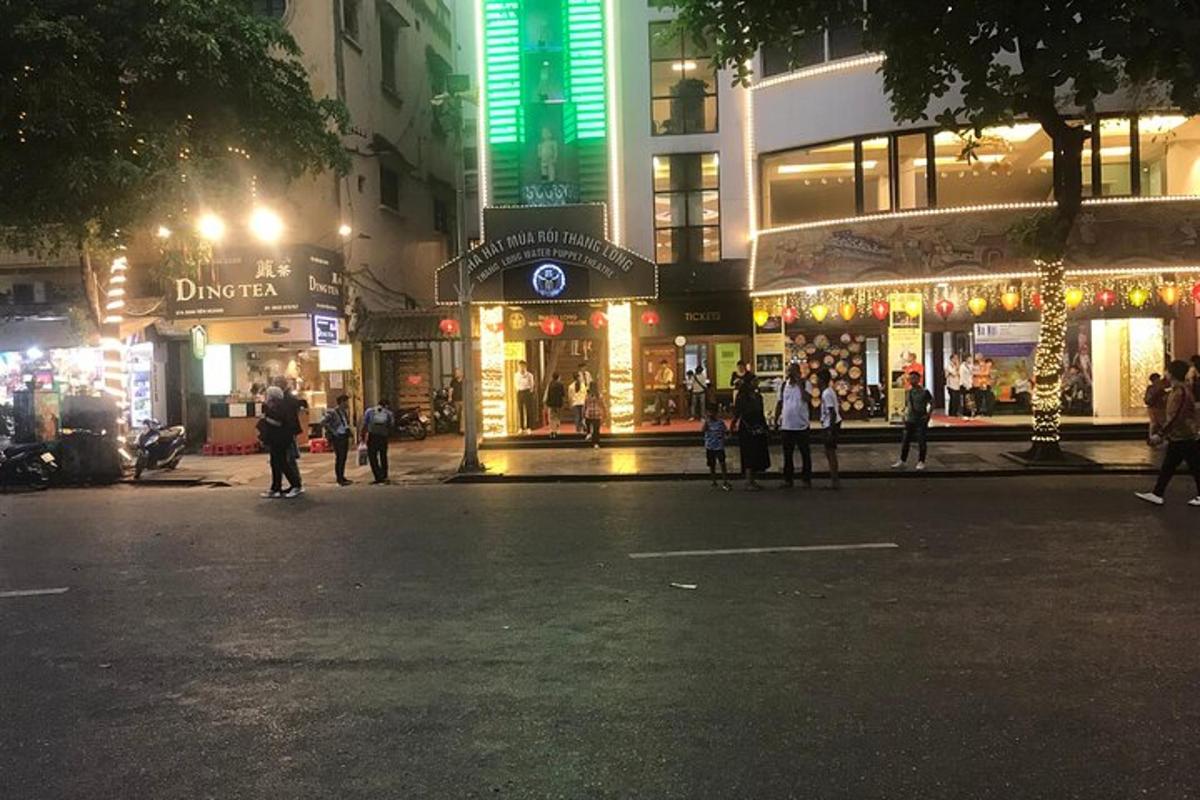 a city street at night with people walking in front of stores
