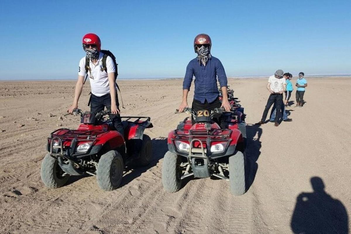 due uomini sono in piedi su quad nel deserto