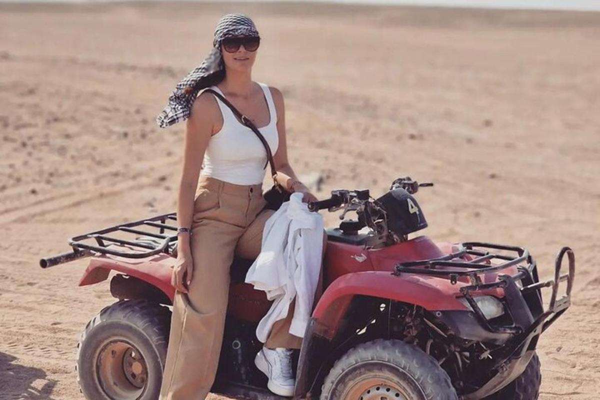 a woman sitting on a quad bike in the sand