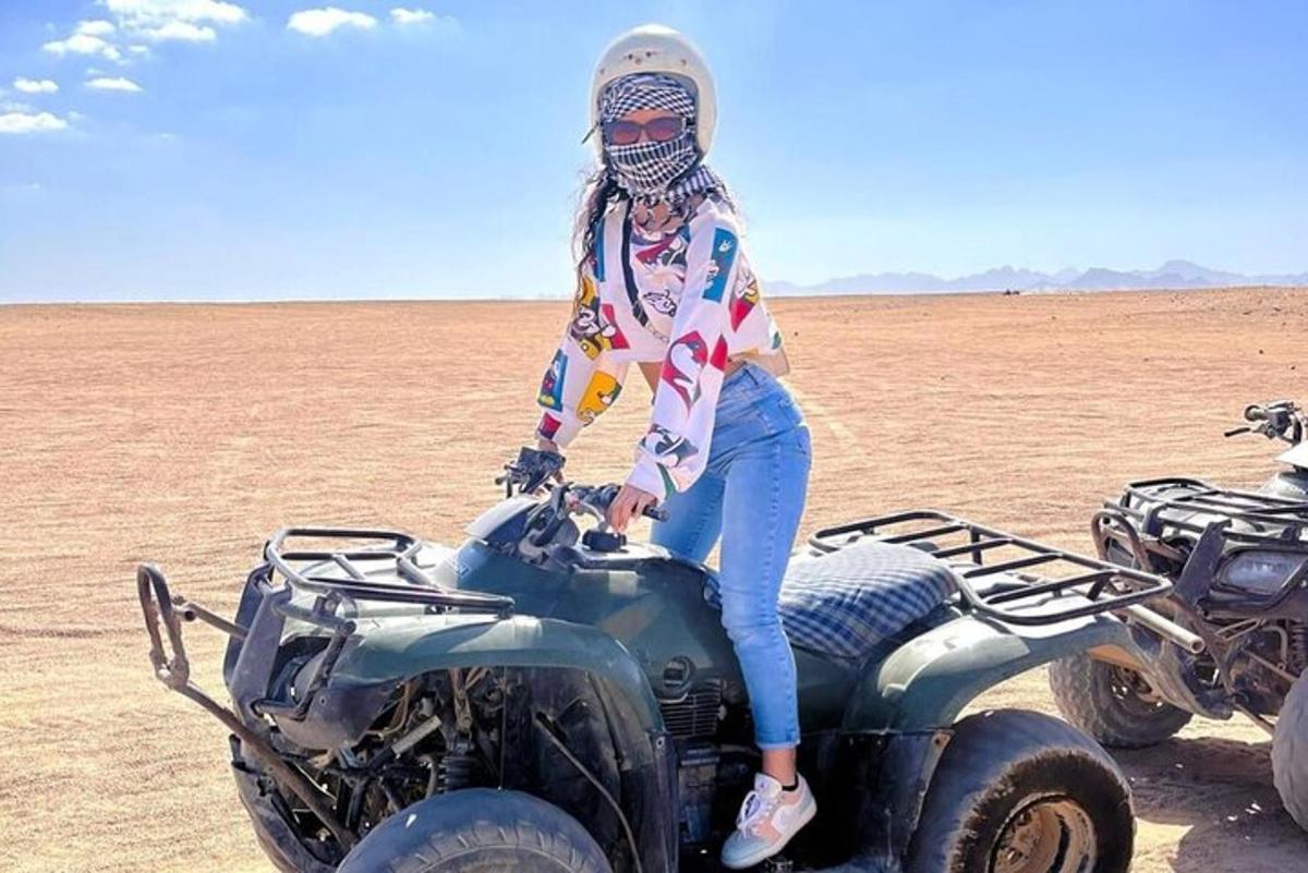 a woman sitting on top of an atv in the desert
