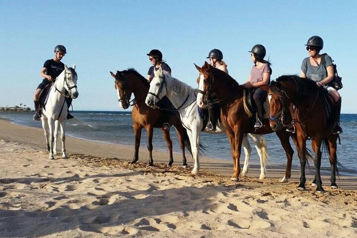 eine Gruppe von Menschen reitet am Strand