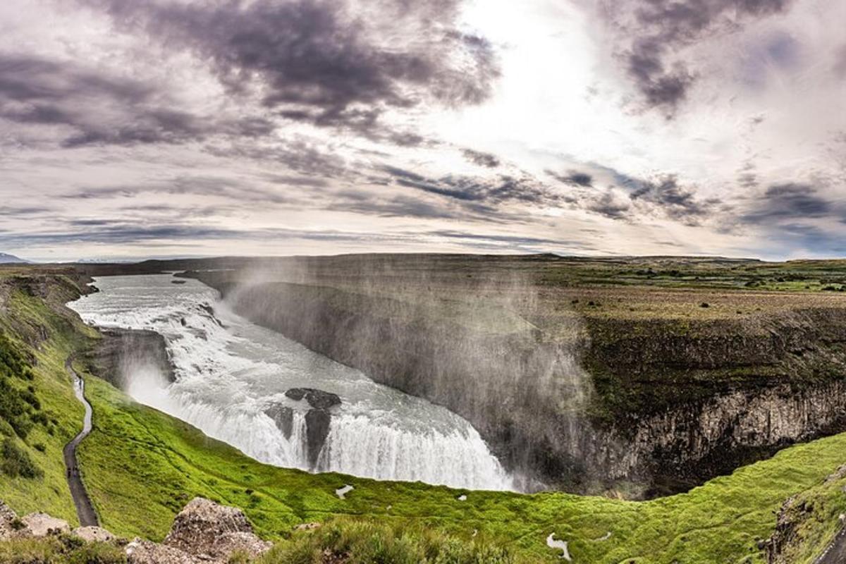 foss á fjallshlíð með skýjuðum himni