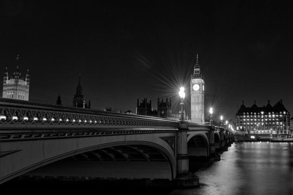 un ponte con una torre dell'orologio e il Big Ben di notte