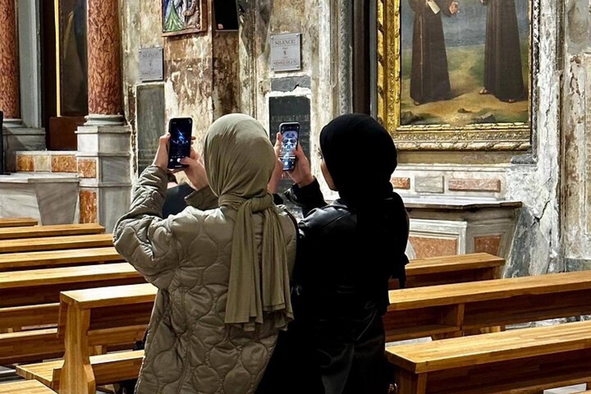 to kvinner som tar bilder av en kirke med mobiltelefonene sine