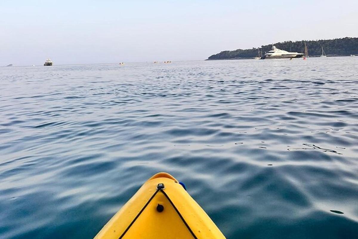 un kayak giallo in acqua con una barca sullo sfondo