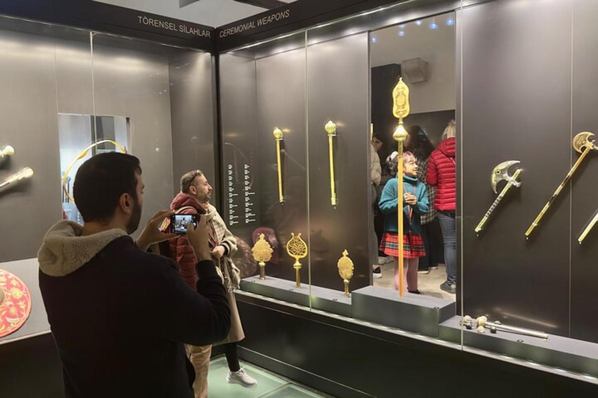 Un hombre tomando una fotografía de una exhibición de artículos de oro.