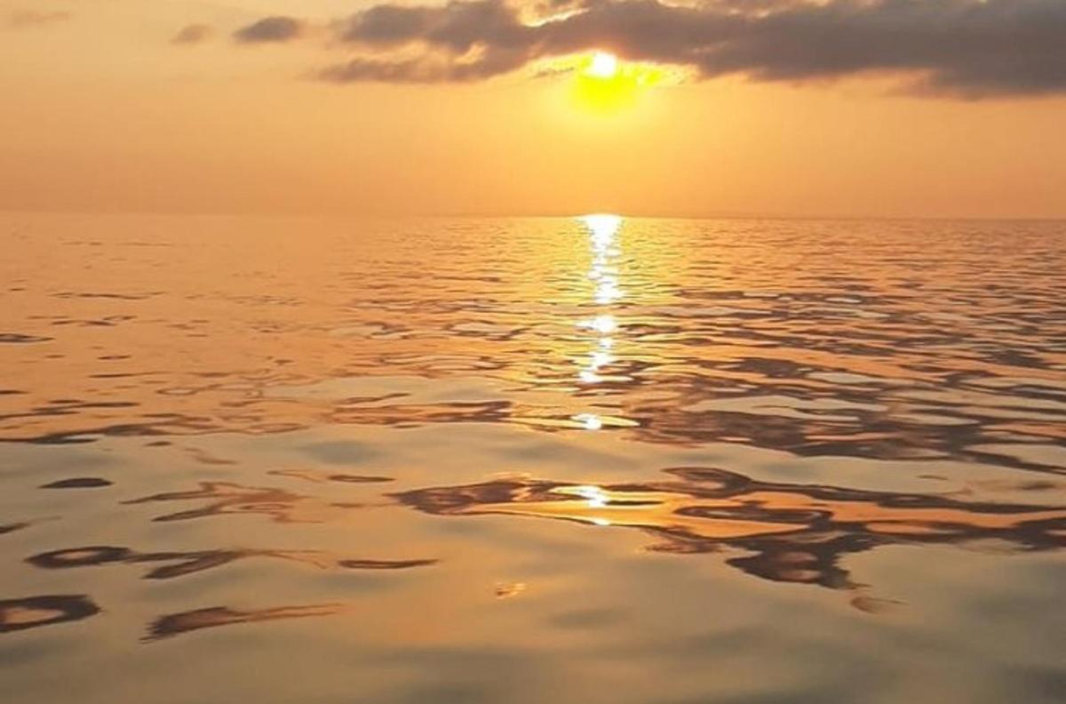 een zonsondergang over het water met de ondergaande zon