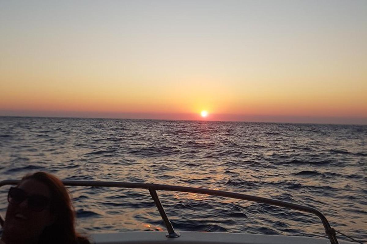žena sediaca na lodi v oceáne pri západe slnka