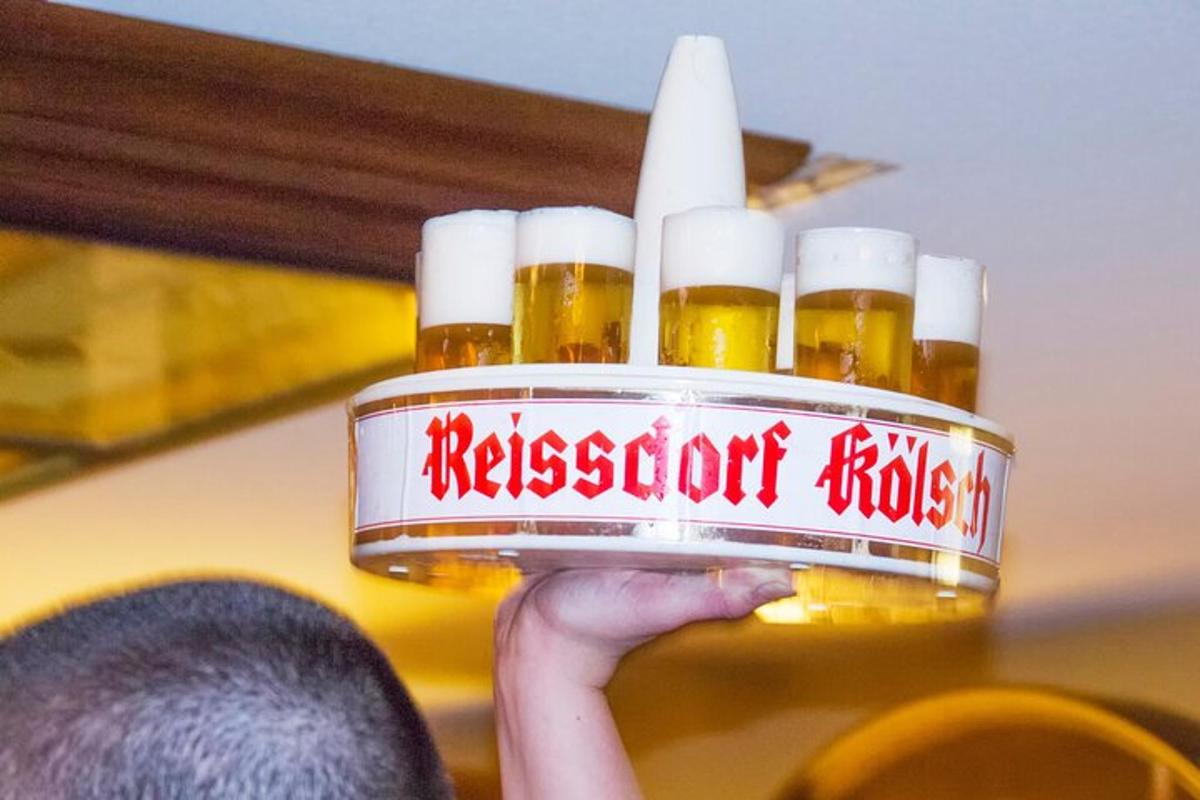 osoba držící podnos se čtyřmi lahvemi piva
