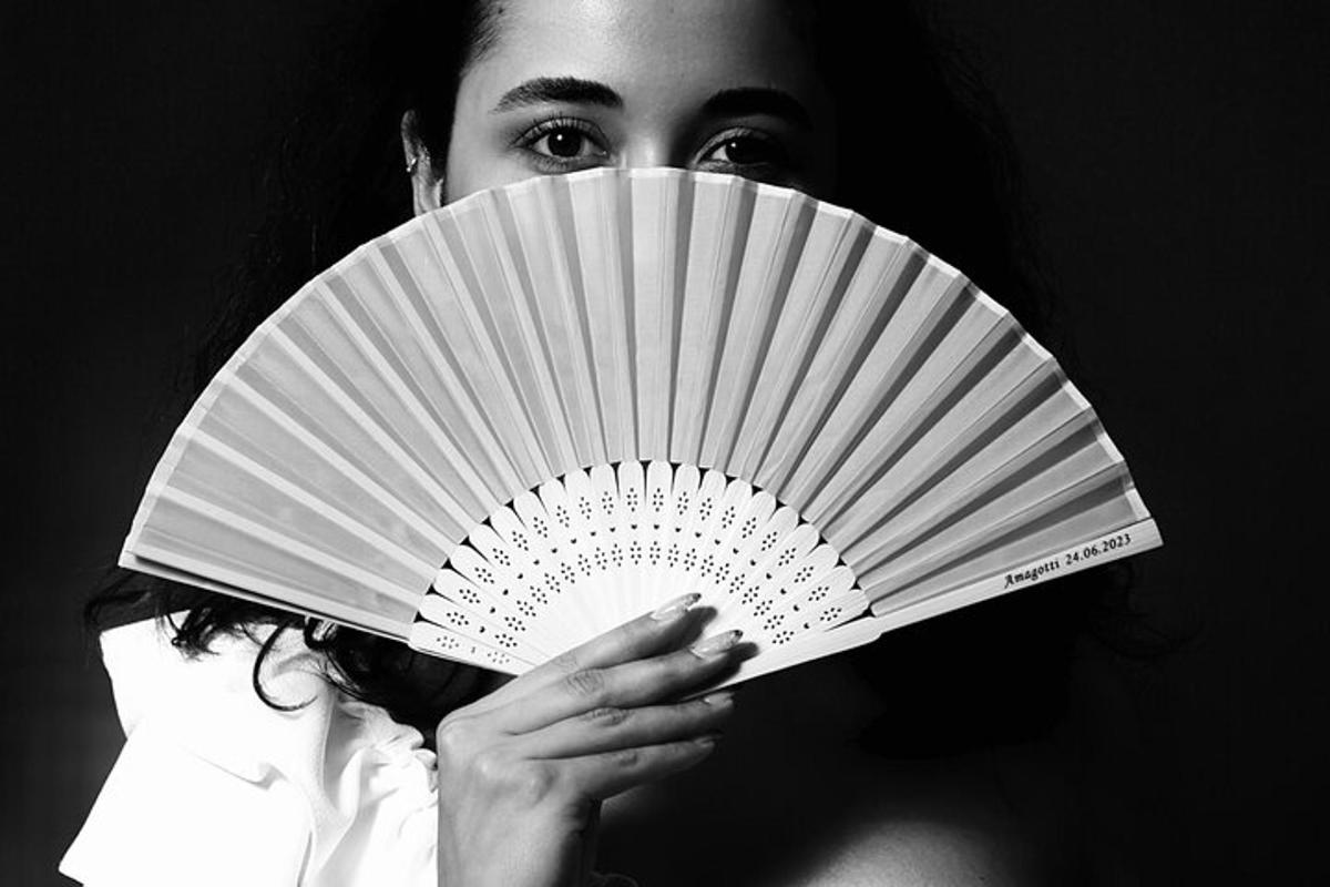 una donna che tiene un ventaglio bianco davanti al viso