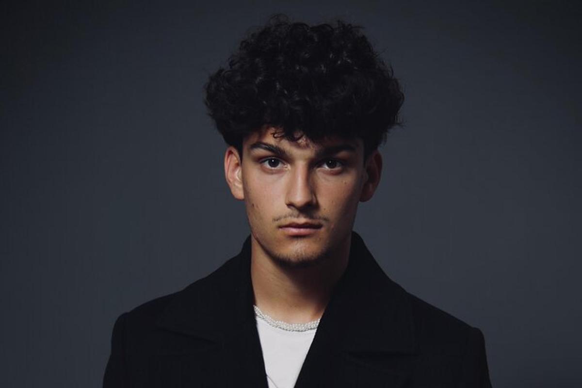un uomo con i capelli ricci che indossa una giacca nera