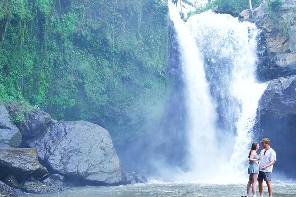 dua orang berdiri di air di depan air terjun