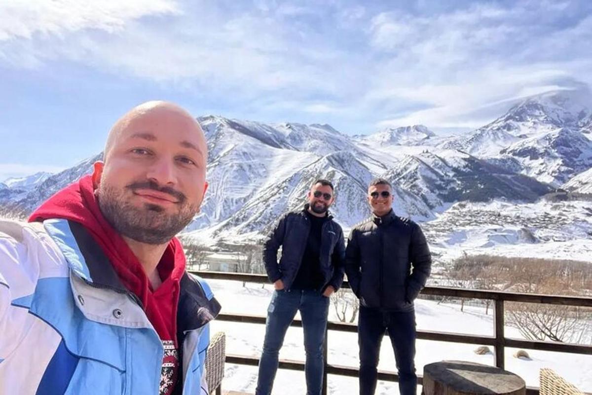 a group of three men standing in front of a mountain