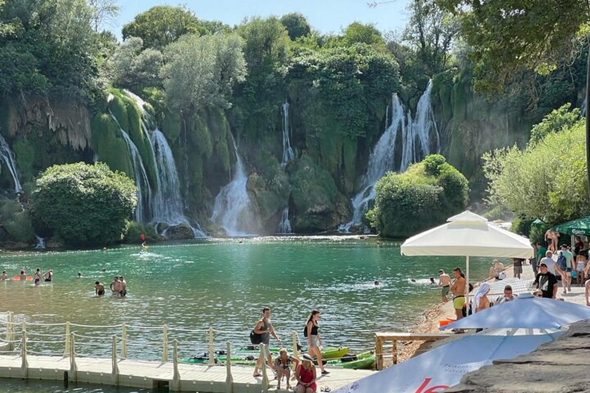 un grup de persones a la platja a prop d'una cascada