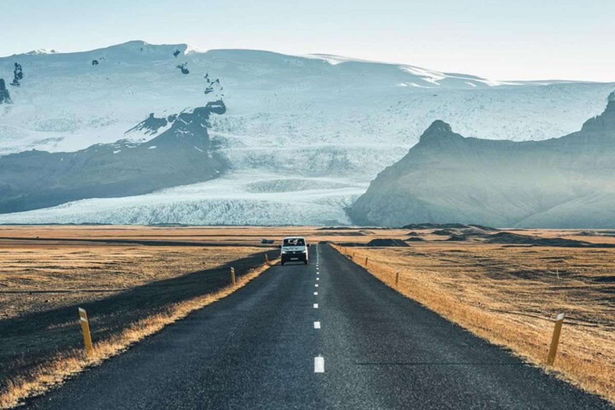 une voiture roulant sur une route avec des montagnes couvertes de neige