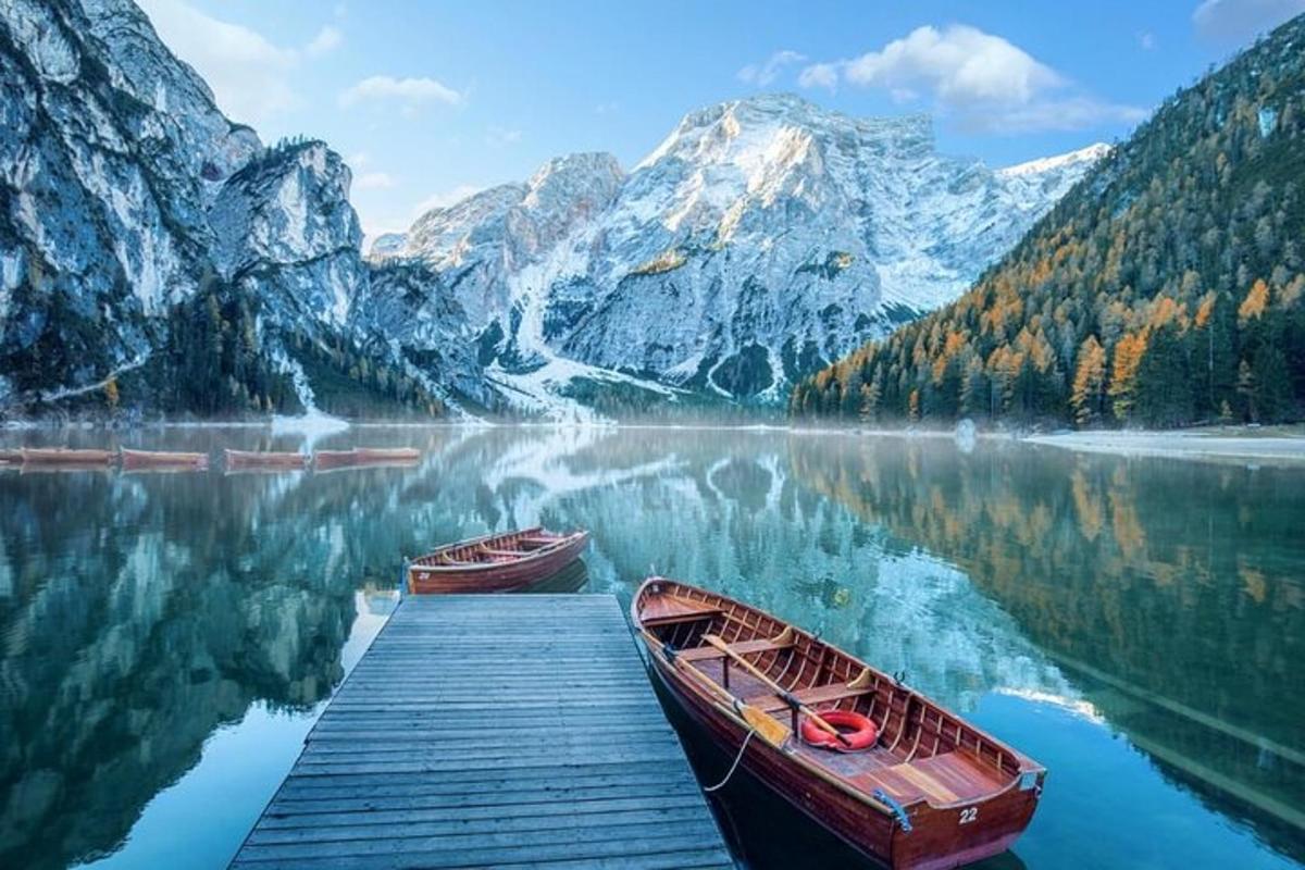dua perahu duduk di dermaga di danau dengan pegunungan