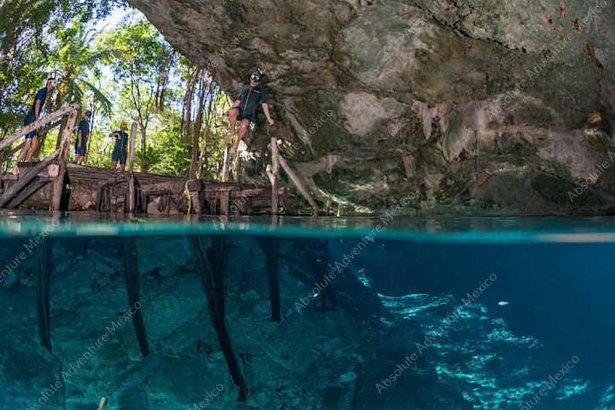 a man jumping into the water from a bridge in a cave