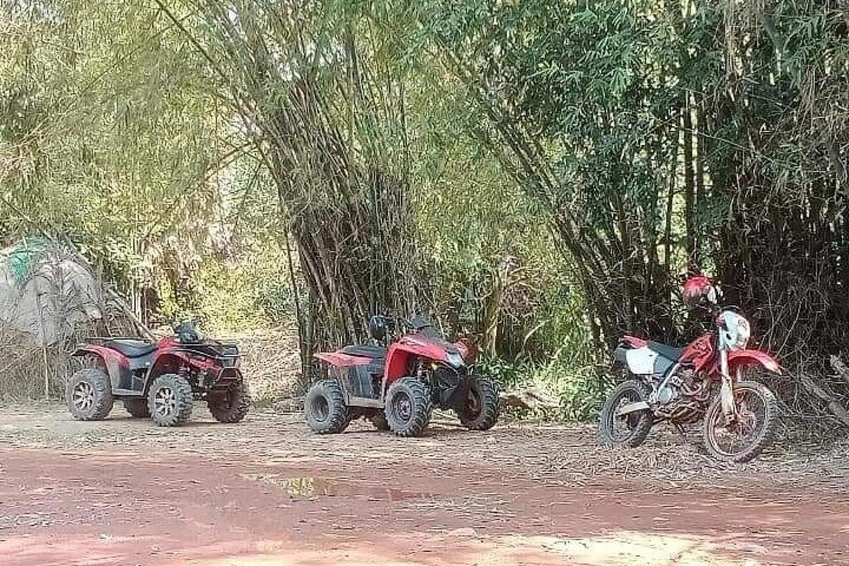 tři čtyřkolky a motocykly zaparkované na nezpevněné cestě