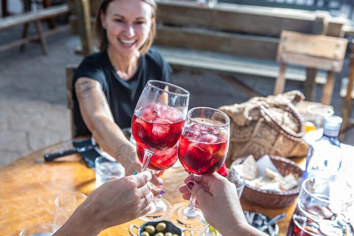 Dos personas sosteniendo copas de vino tinto en una mesa.