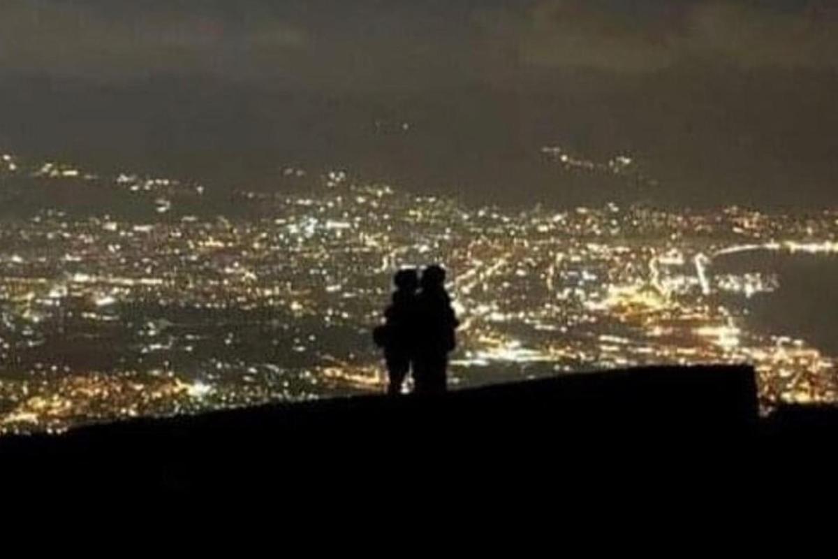 Una pareja parada en la cima de una colina por la noche