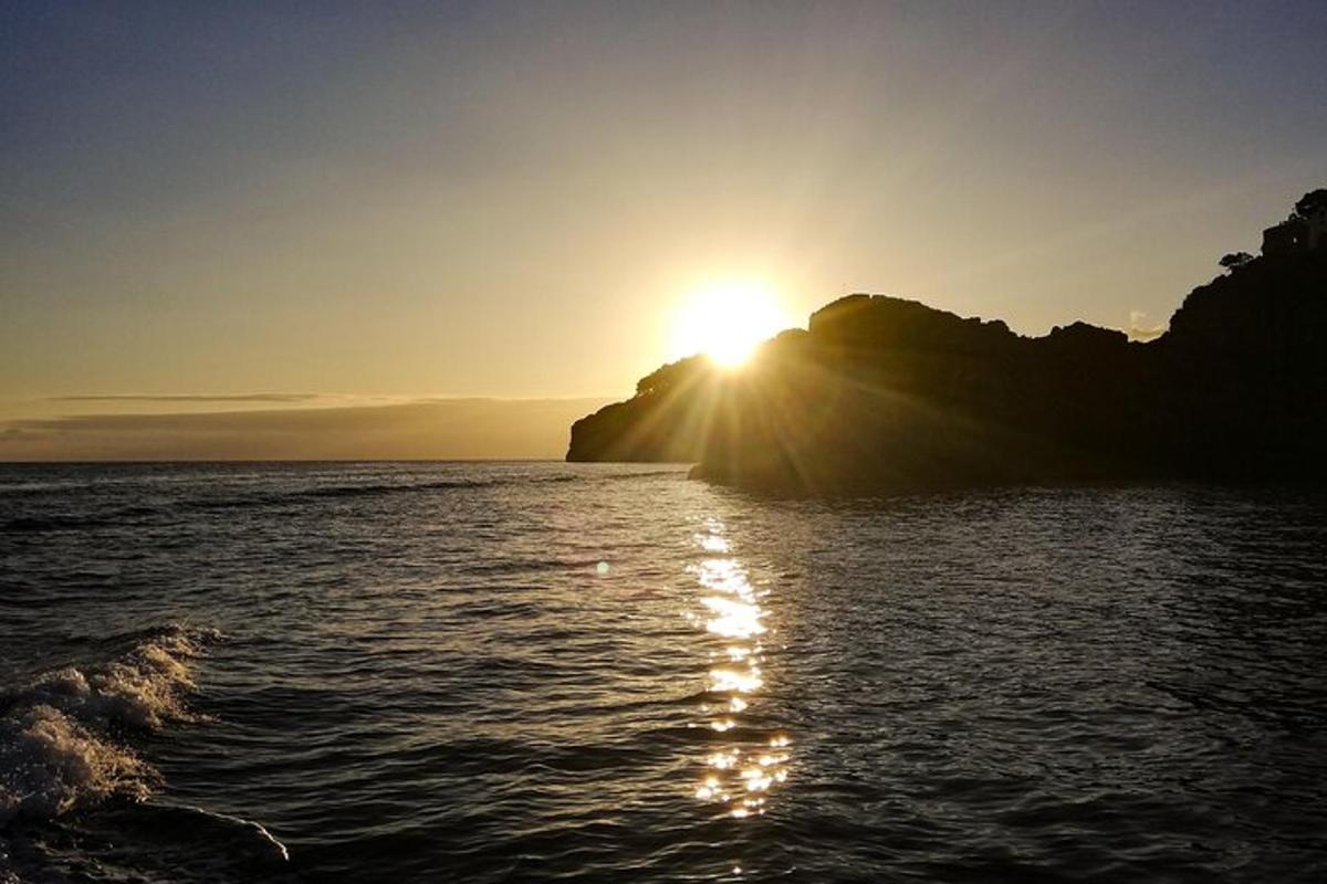 sólsetur á bak við fjall í hafinu