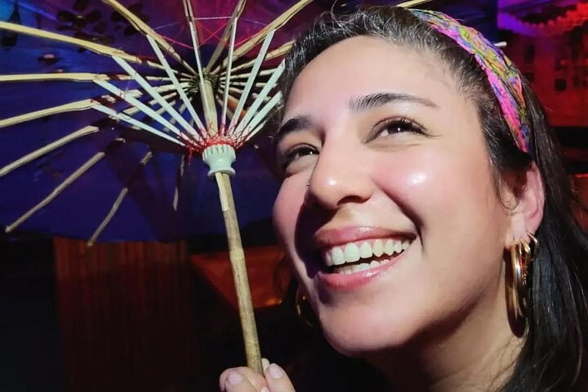 Žena se usmívá a drží modrý deštník