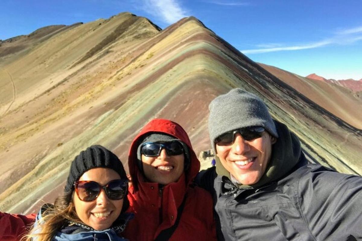 tres personas de pie frente a una montaña