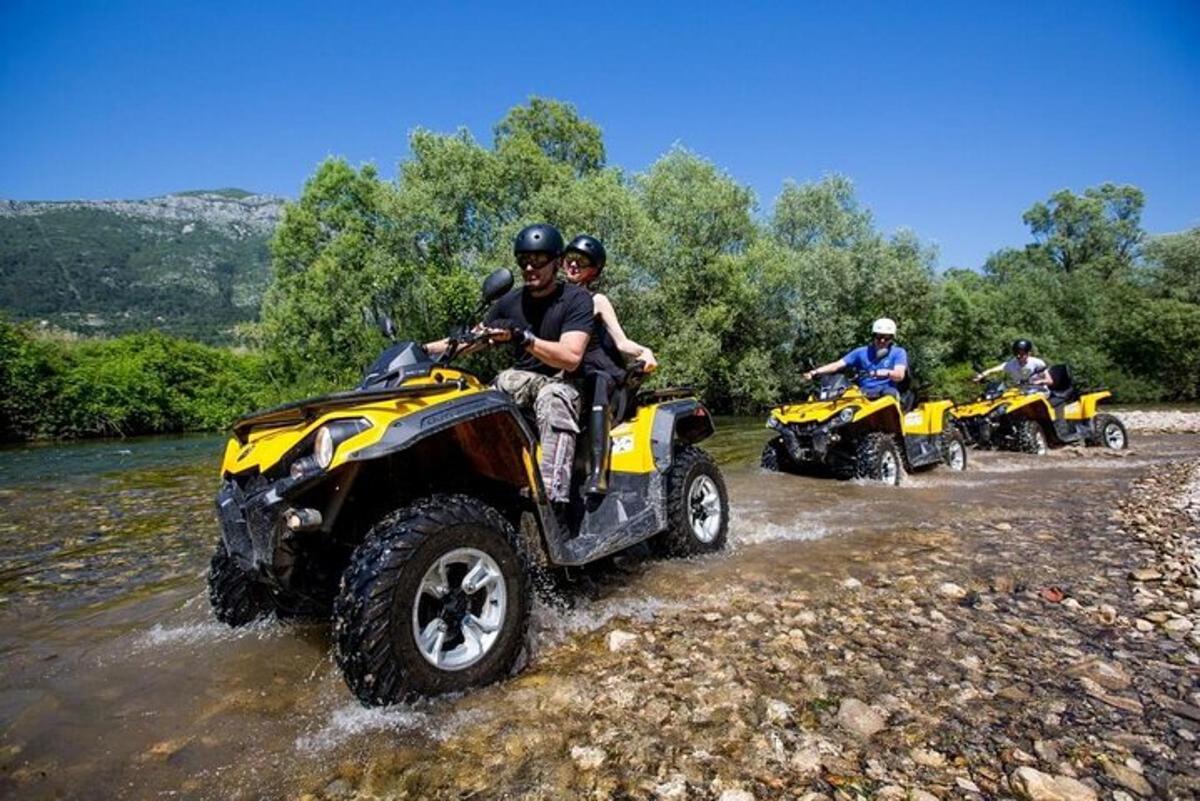 Un grupo de personas viajando en vehículos todo terreno por un río.