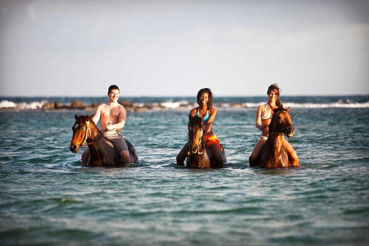 een groep mensen die op paarden in het water rijden