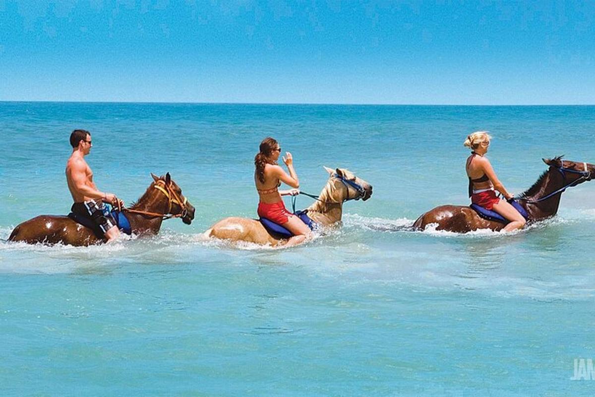 Un grupo de personas montando a caballo en el océano.