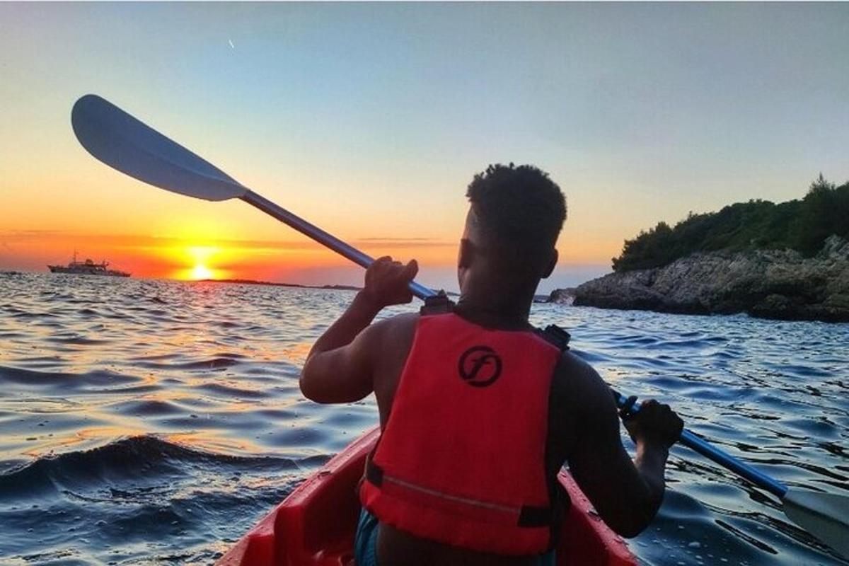 a man in a kayak in the water at sunset