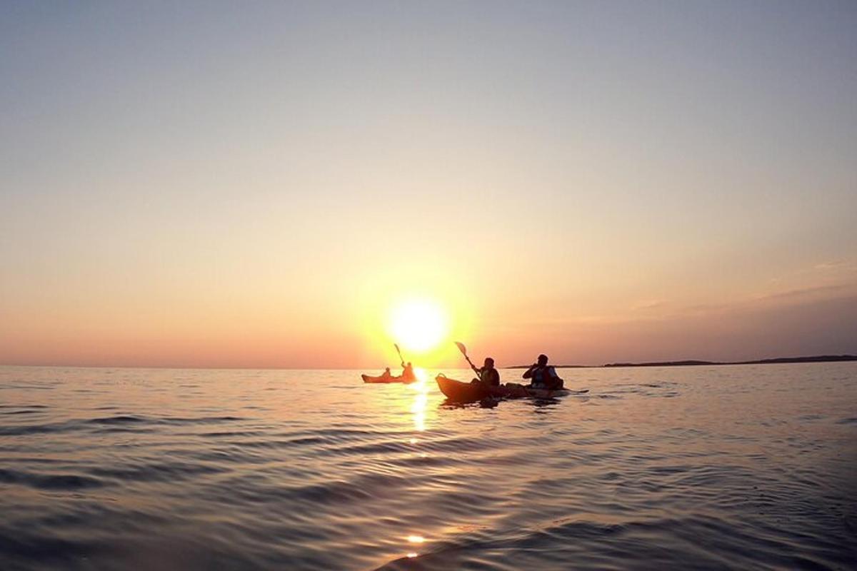 three people in kayaks on the water at sunset