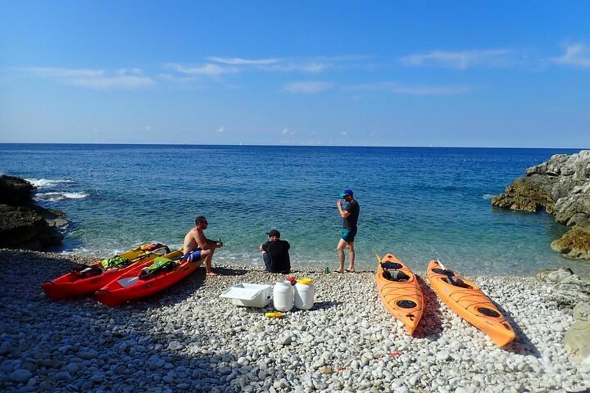 a group of people sitting on a rocky beach with canoes