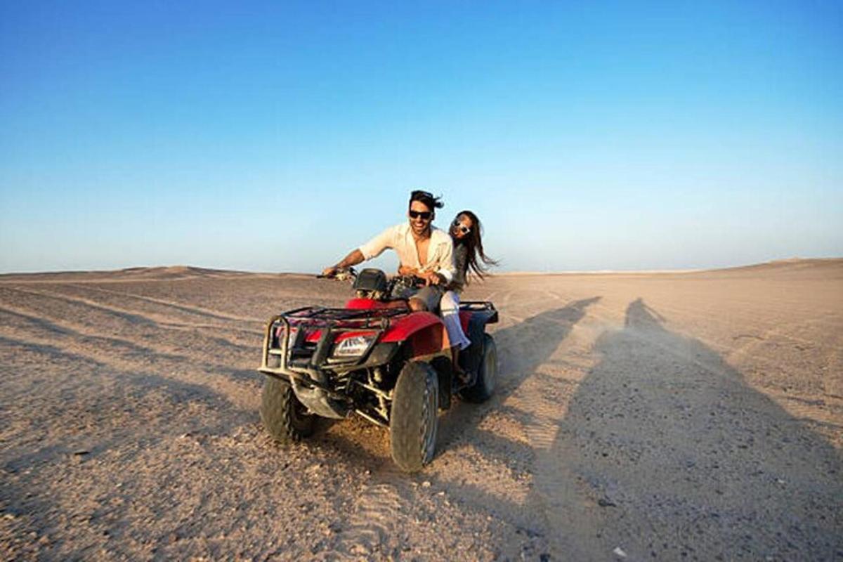 seorang lelaki dan wanita menunggang basikal quad di padang pasir