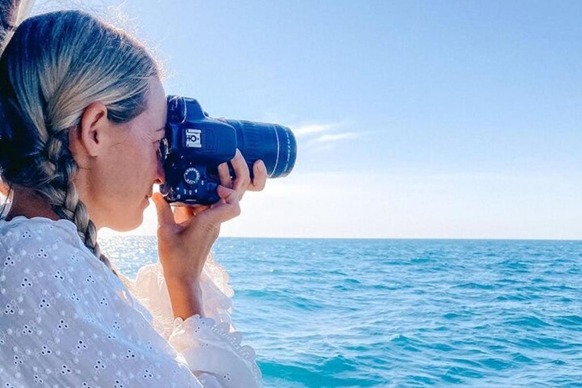 a woman taking a picture of the ocean with a camera