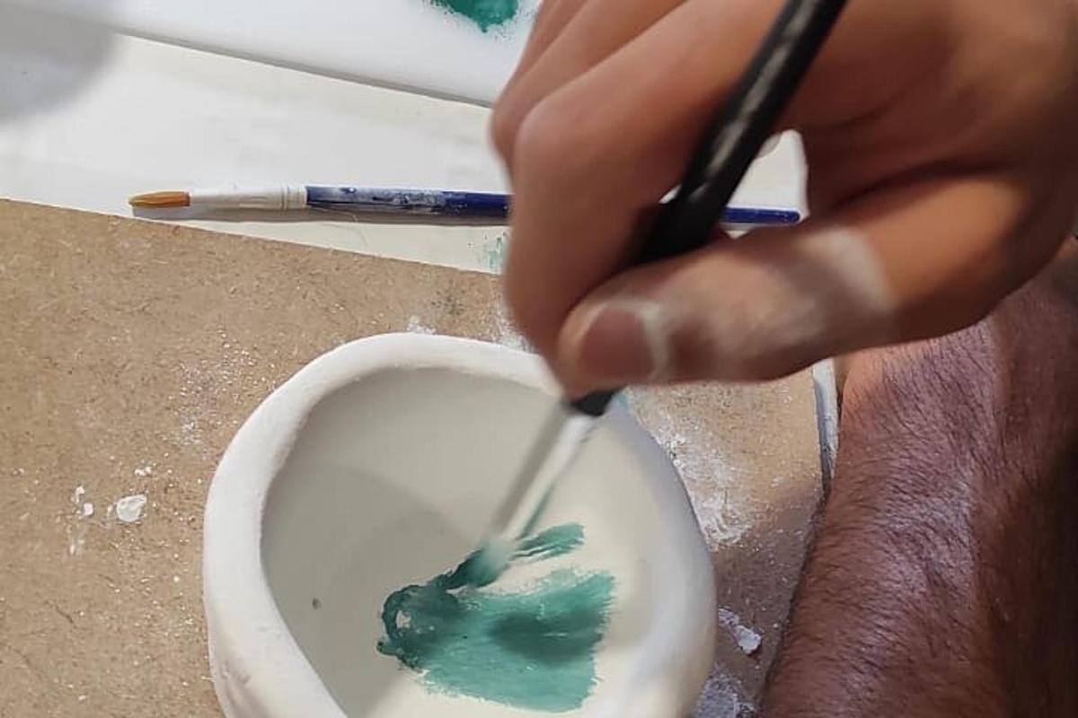 Una persona está pintando un cuenco con un pincel.