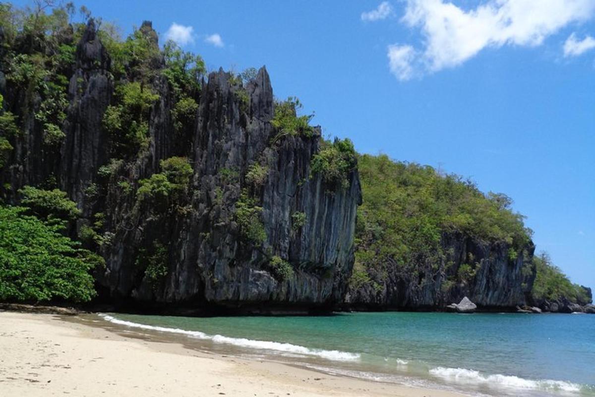 a beach with a rocky mountain in the water