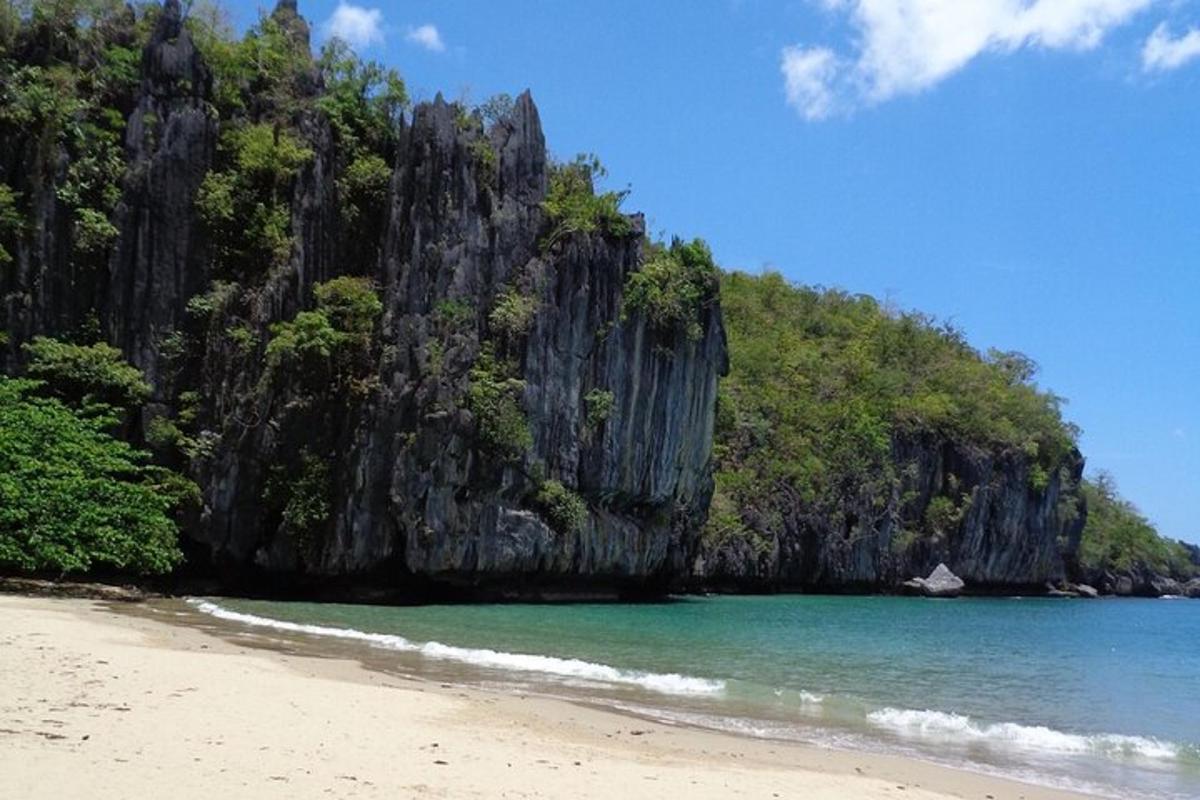a beach with a rocky mountain in the water
