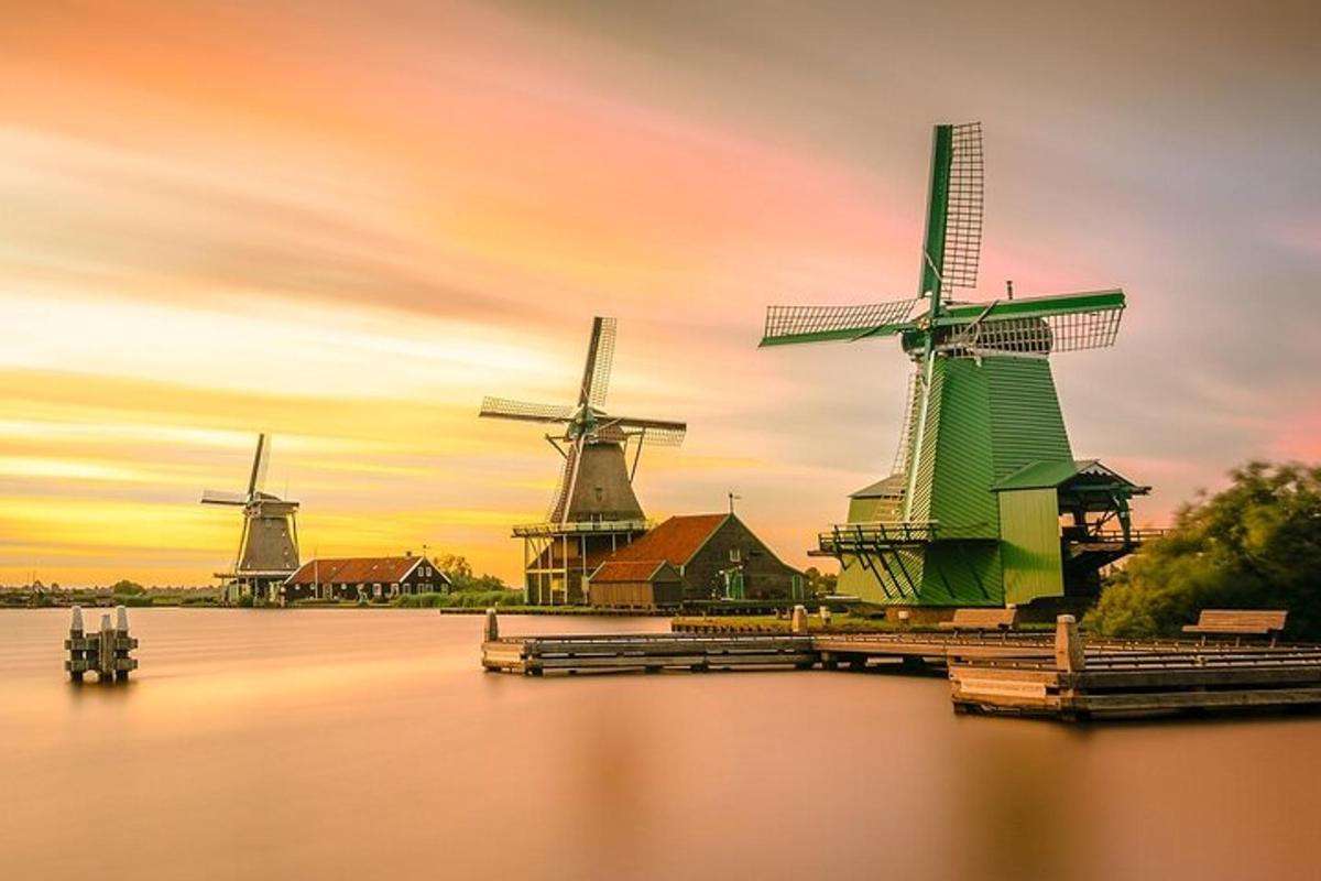 a group of windmills on the water at sunset
