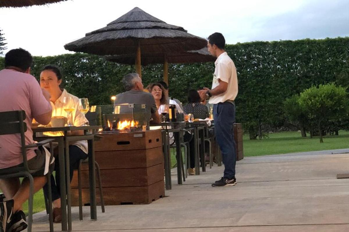 un gruppo di persone sedute ai tavoli sotto un ombrellone